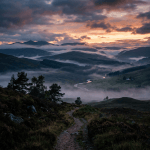 Winding river in misty valley with hills and trees at sunset